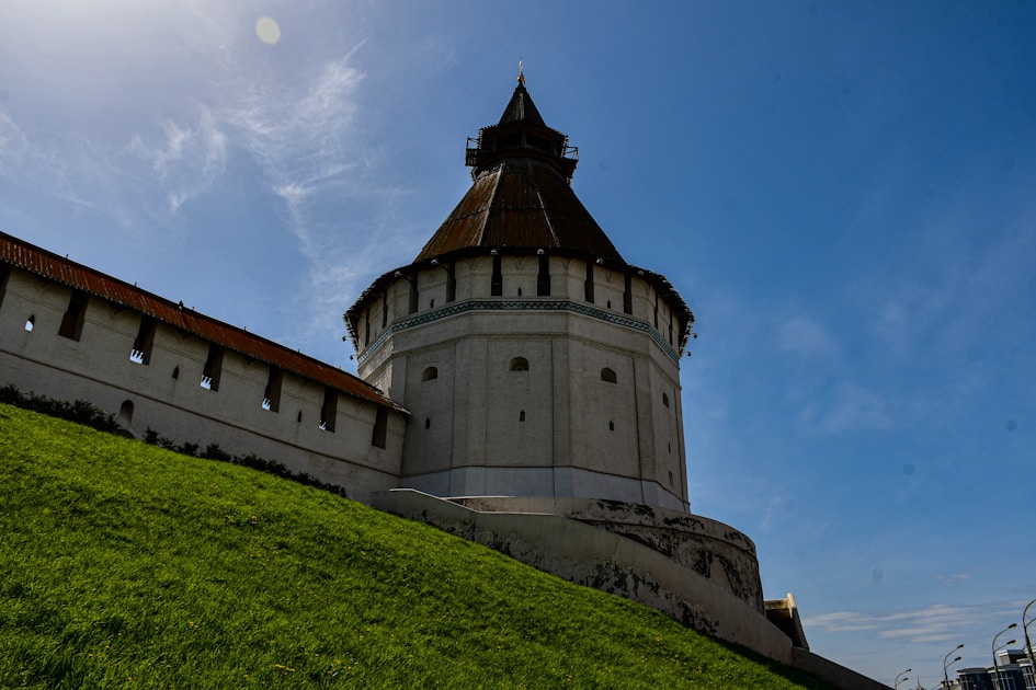 a tall white tower sitting on top of a lush green hillside