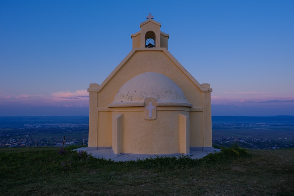 A small church with a bell tower on top of a hill