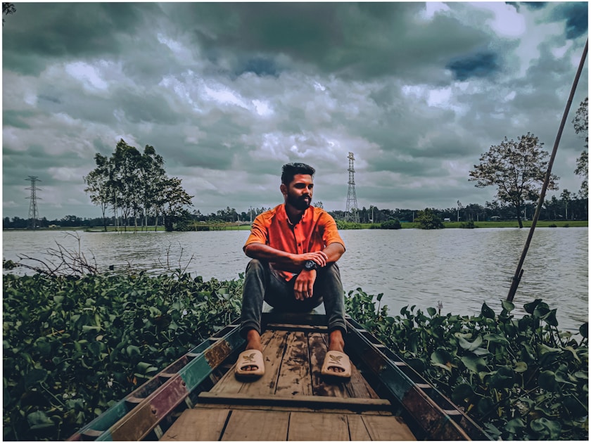 a man sitting in the back of a boat on a river