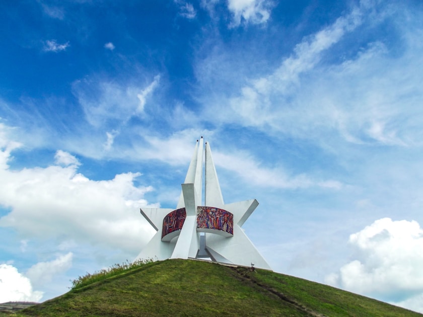 white and red windmill on green grass field under blue sky and white clouds during daytime