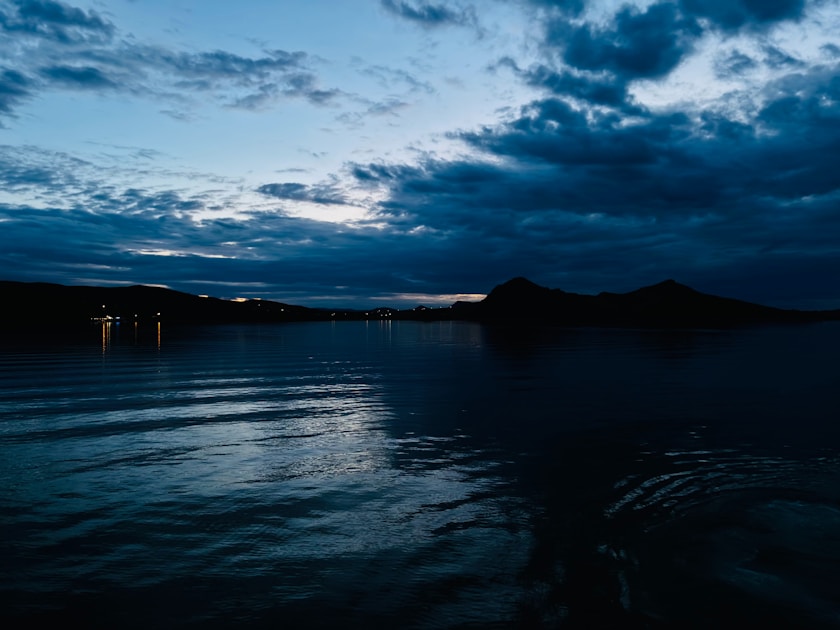 a body of water at night with clouds in the sky