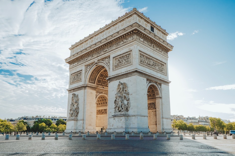 The arc de triomphe in paris under a blue sky.