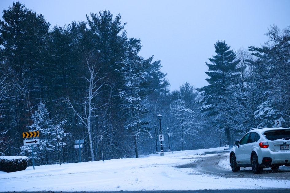 A white car driving down a snow covered road