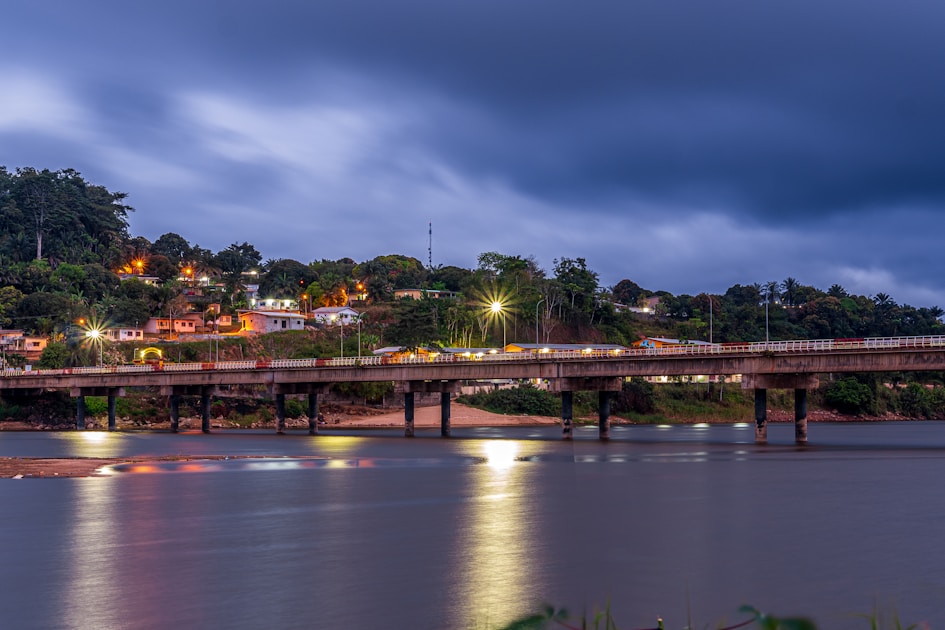 Bridge over river with city lights at dusk