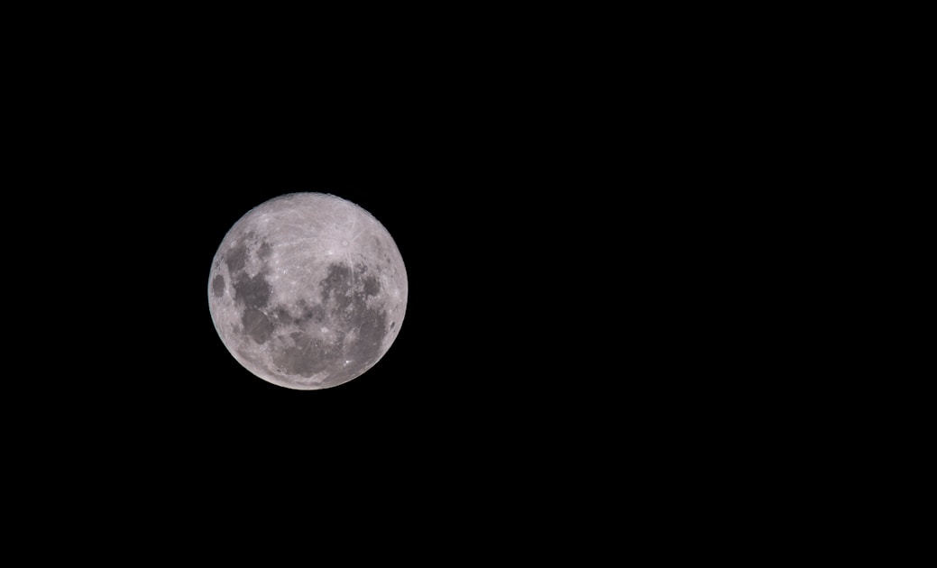a full moon is seen in the dark sky