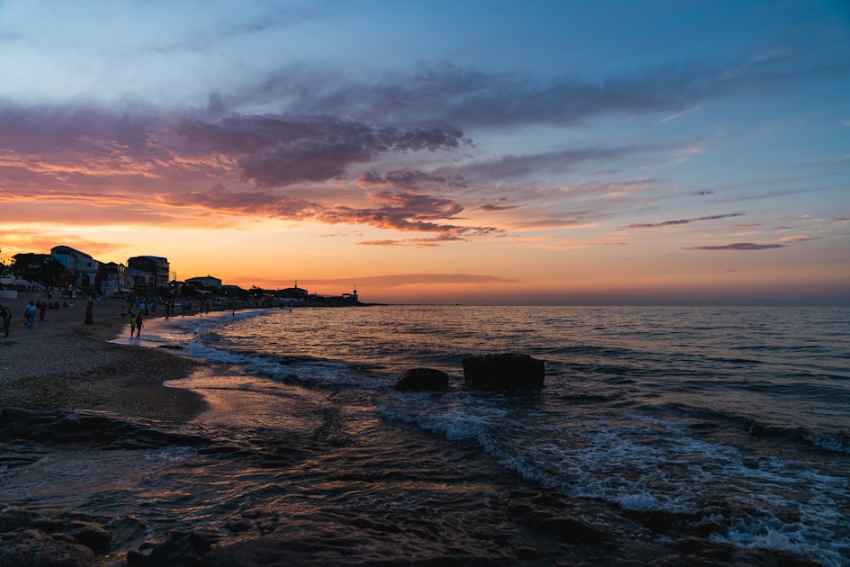 silhouette of buildings near sea during sunset