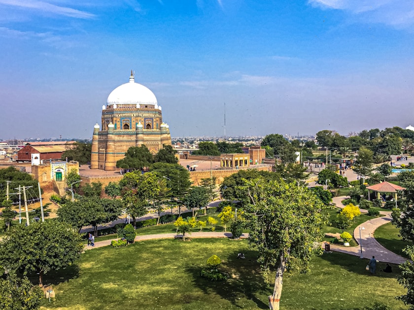green trees near brown concrete building under blue sky during daytime