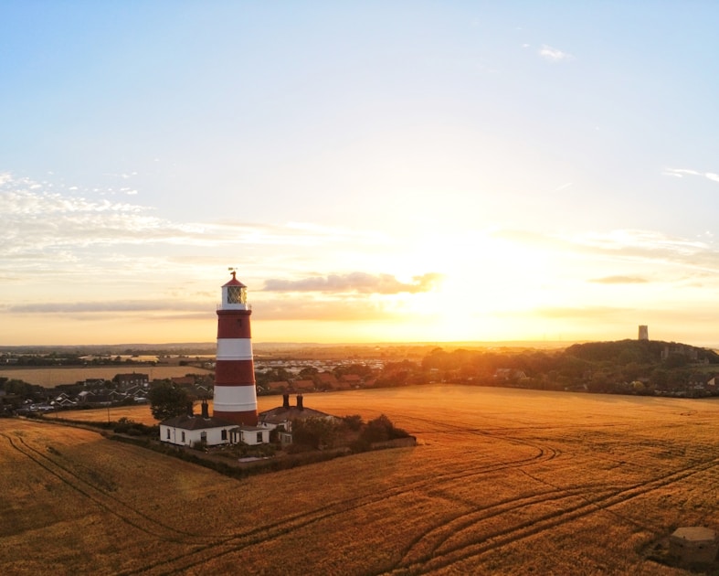 white and black lighthouse on brown sand during sunset