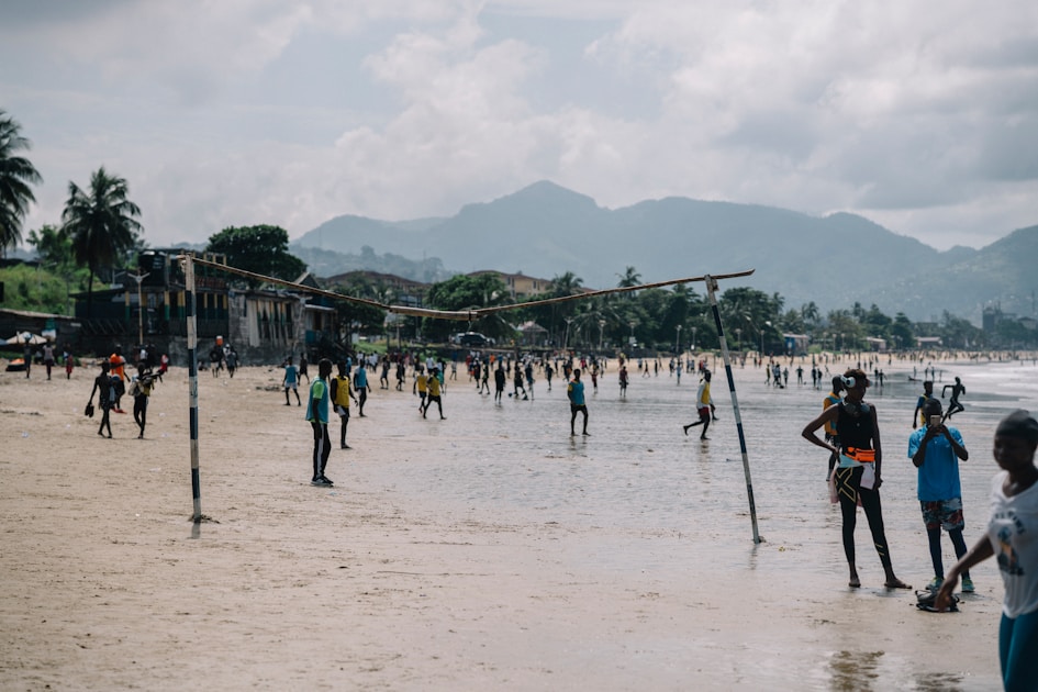 People playing soccer on a tropical beach.