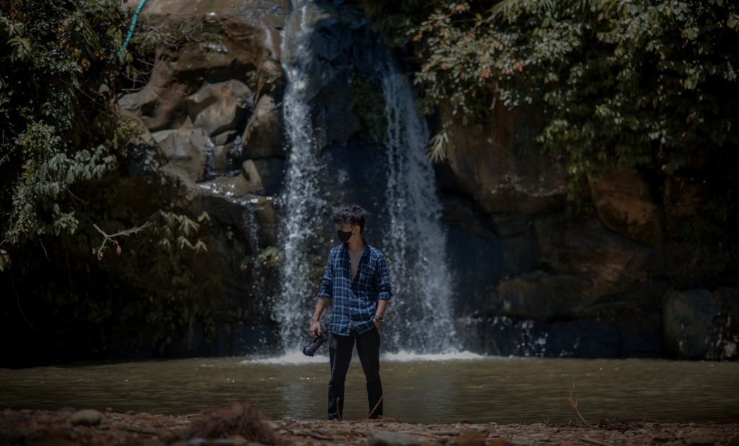 a man standing in front of a waterfall