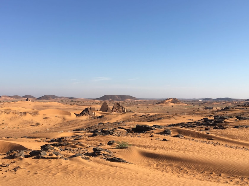 Ancient pyramids rise from a sandy desert landscape