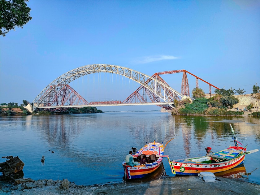 two boats sitting on the shore of a river