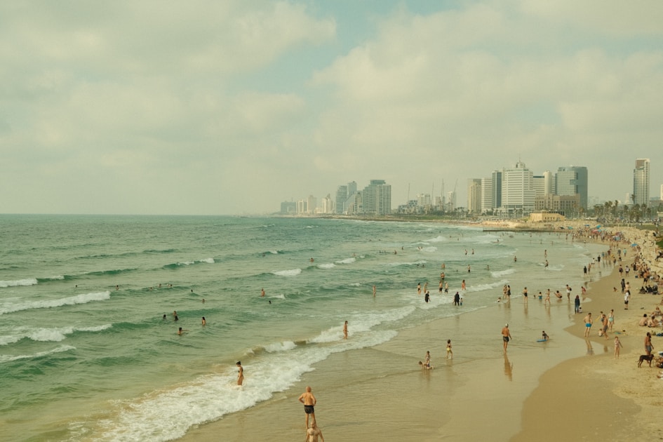 a crowded beach with a city in the background