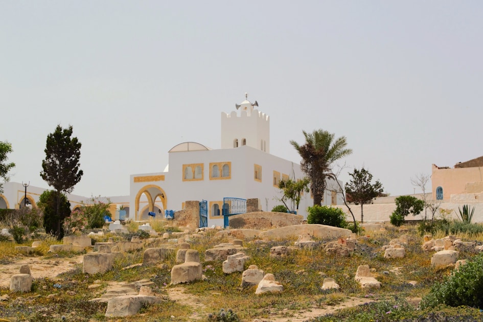A white building with a bell tower on top of a hill